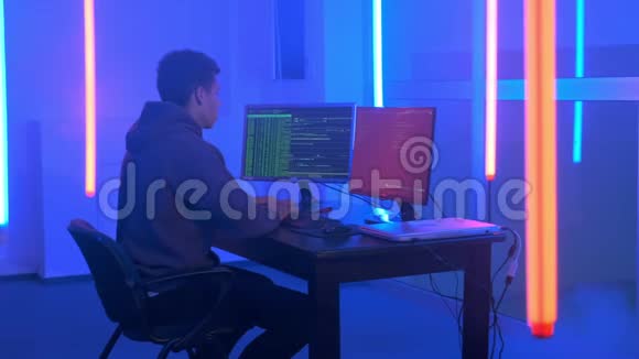 黑人青年用霓虹灯在黑暗的房间里写黑客程序视频的预览图