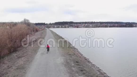 骑自行车的人正在砾石路上沿着大坝骑自行车专业自行车骑手户外培训穿着亮夹克的三项运动员视频的预览图