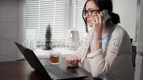 自由职业者的工作理念漂亮的年轻女人在厨房工作左手在电话里说话而且视频的预览图