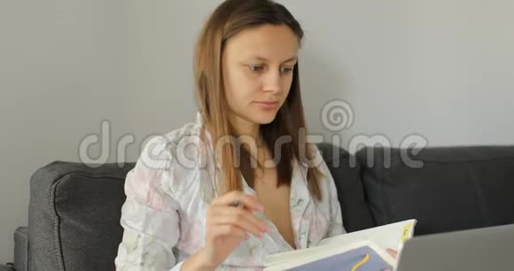 女商人在家里用笔记本电脑工作自由职业者在沙发的笔记本上写一个计划女专业分析图形视频的预览图