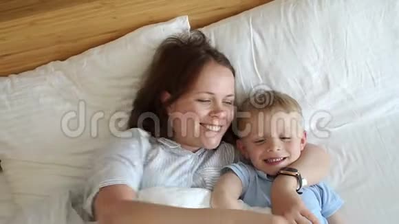 早上妈妈和小儿子在床上的肖像他们醒来拥抱视频的预览图