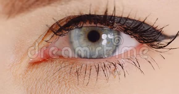 蓝色眼睛的大镜头打开人类虹膜女人的眼睛视频的预览图
