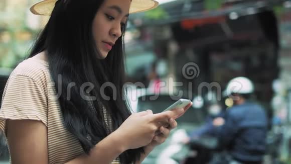 年轻的越南妇女在城里使用智能手机视频的预览图
