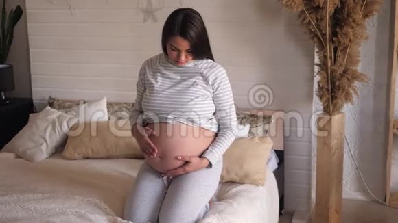 一个孕妇的特写她的肚子在家里的卧室里视频的预览图