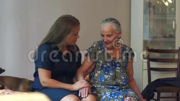 一个年轻的女人在家里沙发上拥抱她九十岁的祖母视频的预览图