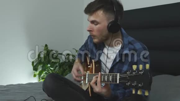 年轻的千禧一代用电吉他演奏的肖像吉他手演奏抒情音乐戴耳机的人会弹吉他视频的预览图