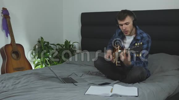 男性有感情地用电吉他唱歌和演奏年轻的帅哥在家弹吉他音乐家学习新歌G视频的预览图