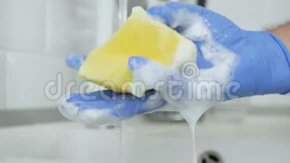 手与橡胶手套使用洗碗机海绵充满泡沫和洗涤剂视频的预览图