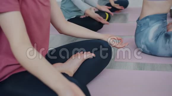 以莲花姿势在瑜伽课上冥想的漂亮年轻女性的慢动作视频的预览图