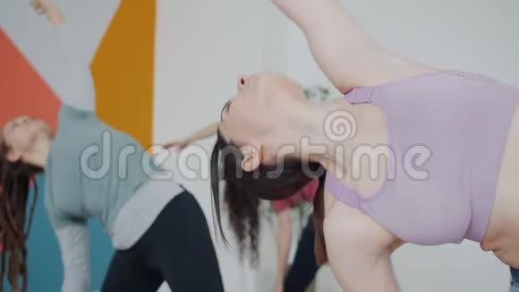 美丽的弹性女孩在时尚运动顶级锻炼瑜伽工作室与一群人视频的预览图
