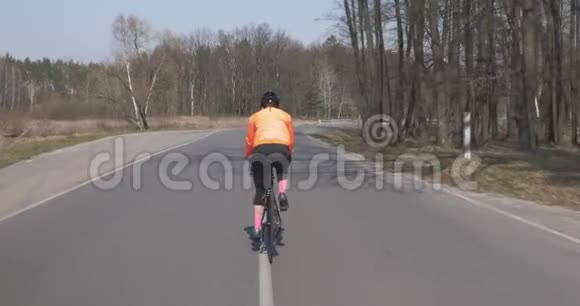 女人骑自行车女性骑在公路自行车上骑自行车戴头盔的女孩三项全能概念视频的预览图