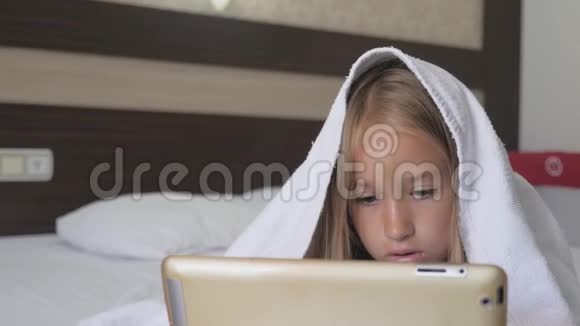 十几岁的女孩在床上玩社交网络上的平板电脑特写小女孩在数字平板上看视频视频的预览图