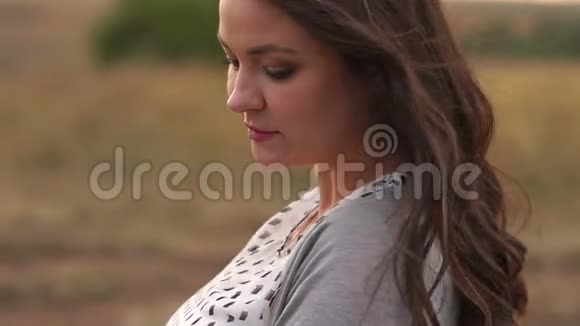 日落时分一个年轻的女孩在田野里留着长长的深色流动的头发视频的预览图