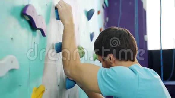 漂亮的运动员在健身房室内攀岩人造岩石专注于训练视频的预览图
