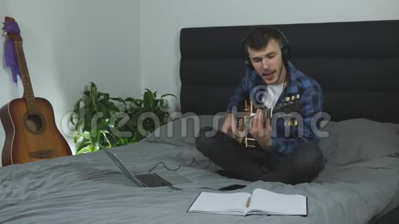 音乐作曲家创作抒情音乐戴耳机的年轻人用电吉他学习新和弦音乐家用吉他弹视频的预览图