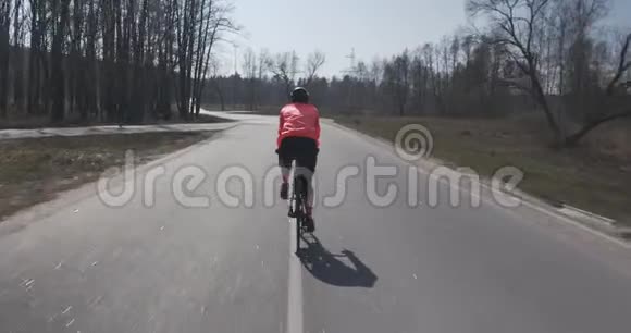 女人骑着自行车使劲蹬戴头盔的女三项运动员骑自行车女运动员在空路上骑自行车三项全能比赛视频的预览图