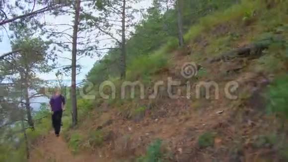 一个背着背包的女孩沿着陡峭斜坡的小径奔跑视频的预览图