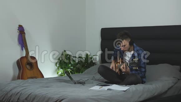 耳机里的吉他手用电吉他演奏男千禧一代演奏现代生活中的乐器新歌视频的预览图