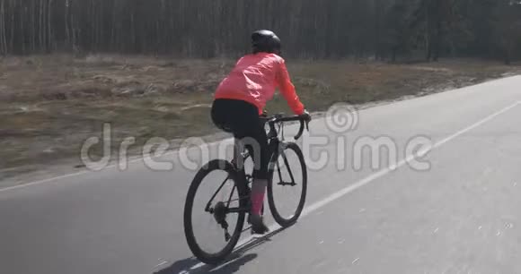 女人骑自行车女脚踏车骑自行车的人独自骑在空路上三项运动员循环训练自行车和t视频的预览图