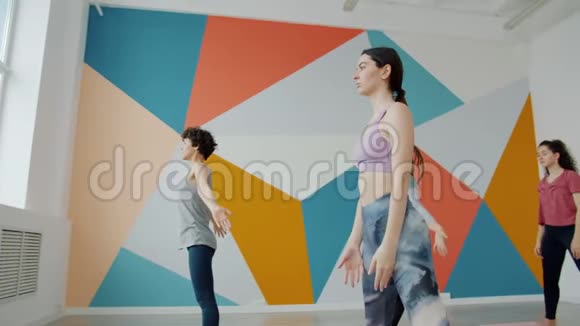 在宽敞的健身房训练中女孩和男人一起在瑜伽练习中向前弯曲视频的预览图