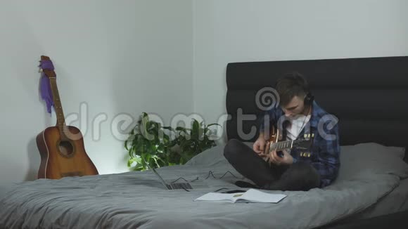 用电吉他独奏的人男吉他手在家中独自表演坐在床上音乐家情绪表演视频的预览图