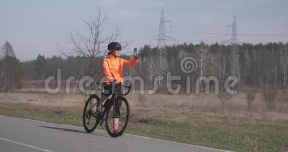 女骑自行车的人在电话里自拍骑自行车的女人在智能手机上拍照戴着自行车头盔的女孩拍照Spo视频的预览图