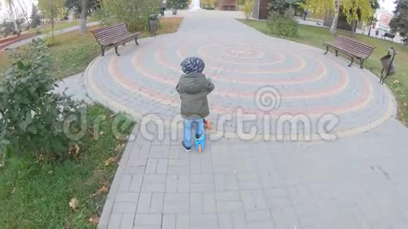 小男孩在城市公园里学骑滑板车主动休闲和儿童户外运动视频的预览图