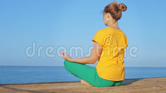 穿着五颜六色衣服的年轻女子在海边或海洋上练习瑜伽视频的预览图