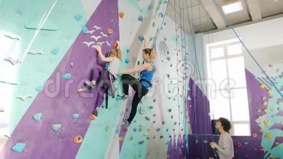 女人和小孩喜欢在体育馆里攀岩而同伴们则拿着绳子站在下面视频的预览图