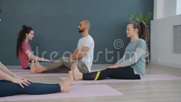 有魅力的女人和男人在课堂上做瑜伽伸展腿坐在垫子上视频的预览图