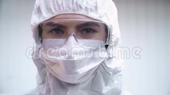 穿着防护服口罩和眼镜的医生看着摄像机白色背景视频的预览图