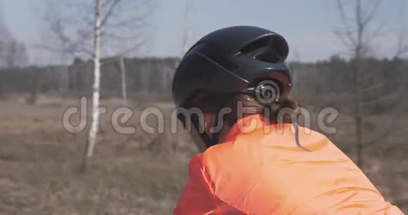 戴头盔的女人骑着公路自行车女自行车手在骑马女孩骑自行车后侧靠近三项全能概念视频的预览图