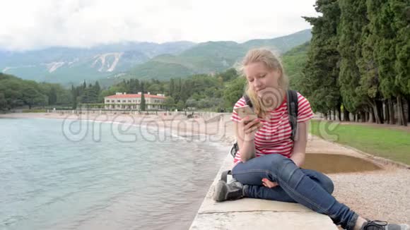 坐在海边和山上用智能手机刷卡的女孩视频的预览图