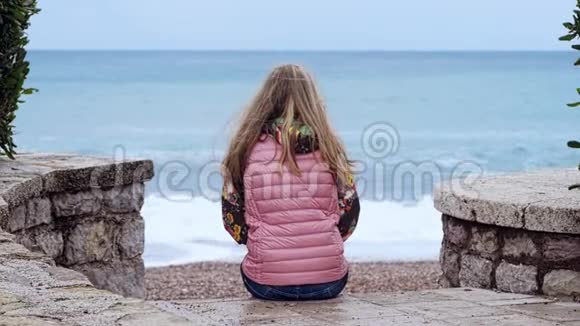 孤独的女孩坐在靠海的楼梯上视频的预览图
