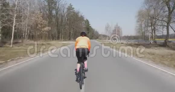 女人骑自行车女性骑自行车三项运动员在自行车上硬踏板戴头盔的女孩在户外骑马三项全能概念视频的预览图