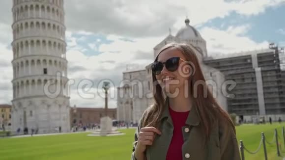 戴着太阳镜的旅游女孩在可爱的白天在比萨斜塔附近散步视频的预览图