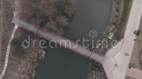 女性在公园与河流空中俯视的桥梁上奔跑女人做户外运动无人驾驶的女孩在公园W跑视频的预览图
