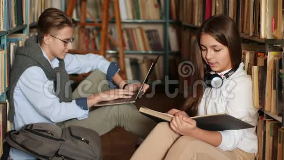 两个朋友看书在图书馆用笔记本电脑视频的预览图