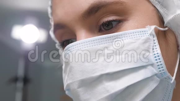 女外科医生戴着外科口罩低头看病人然后站在班长或旁边行动视频的预览图