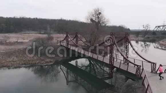 女人正在跨河的桥上奔跑空中无人机的视野布鲁内特女运动员在公园里与河流和长廊跑步女孩公关视频的预览图