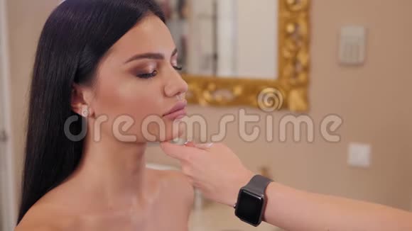 化妆师正在给她的顾客化妆并在脸上喷上喷雾视频的预览图