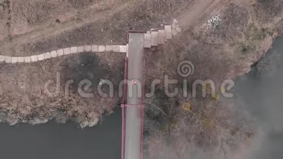 从空中俯瞰女子过桥穿着鲜艳夹克的性感女运动员在城市公园的跨河大桥上奔跑视频的预览图