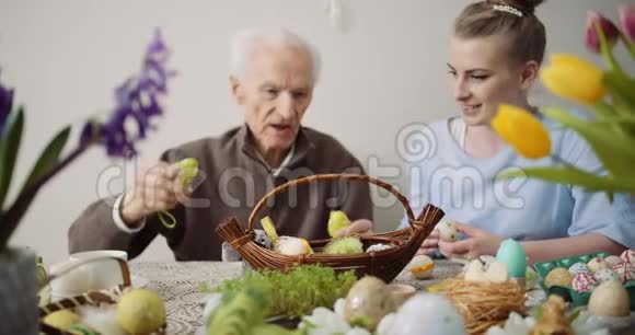 老人和年轻妇女把复活节彩蛋放进篮子里视频的预览图