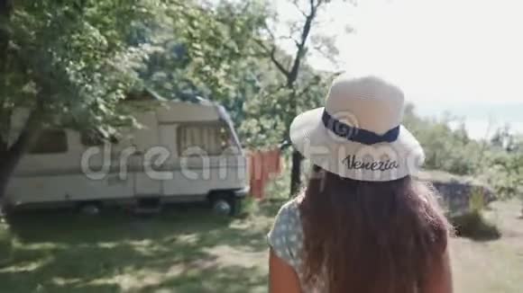跟着一个戴着帽子穿着浪漫服装的女人去森林里的露营车视频的预览图
