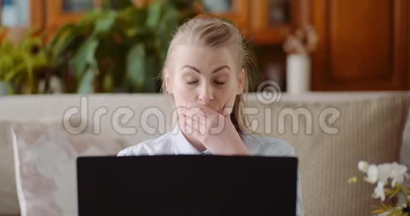 微笑的女人在家里的办公室用笔记本电脑工作视频的预览图