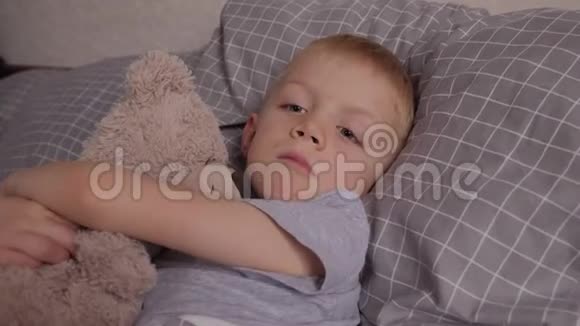 一个带水痘的小男孩和他最喜欢的泰迪熊躺在床上视频的预览图