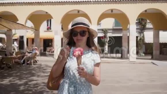 戴帽子戴太阳镜的女孩走路在街机背景上吃红色冰淇淋视频的预览图