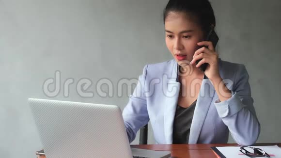 年轻的亚洲妇女拿起电话与客户谈谈工作的进展视频的预览图