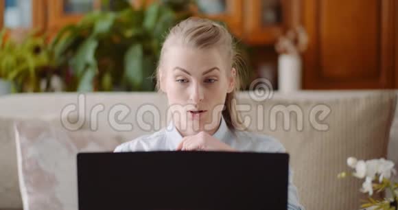微笑的女人在家里的办公室用笔记本电脑工作视频的预览图