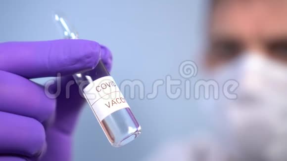 冠状病毒疫苗安瓿在医生手中面罩和防护医疗手套在蓝色背景视频的预览图